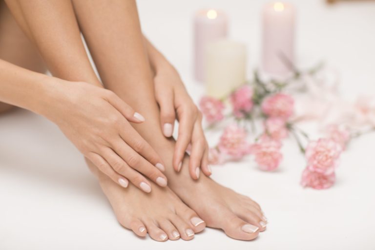 The picture of ideal done manicure and pedicure. Female hands and legs in the spa spot.